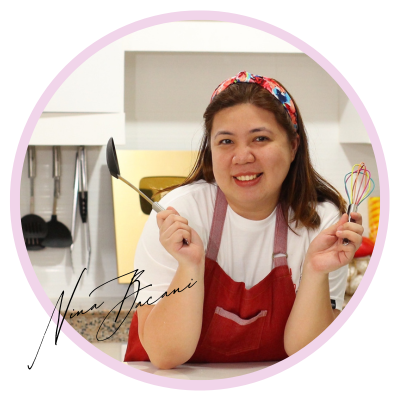Nina Bacani smiling in a kitchen while holding cooking tools